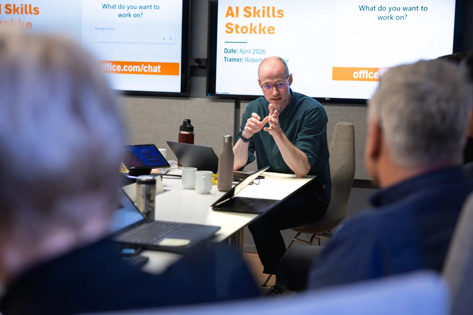 Robert opens an AI Skills session at a conference table with two screens in the background