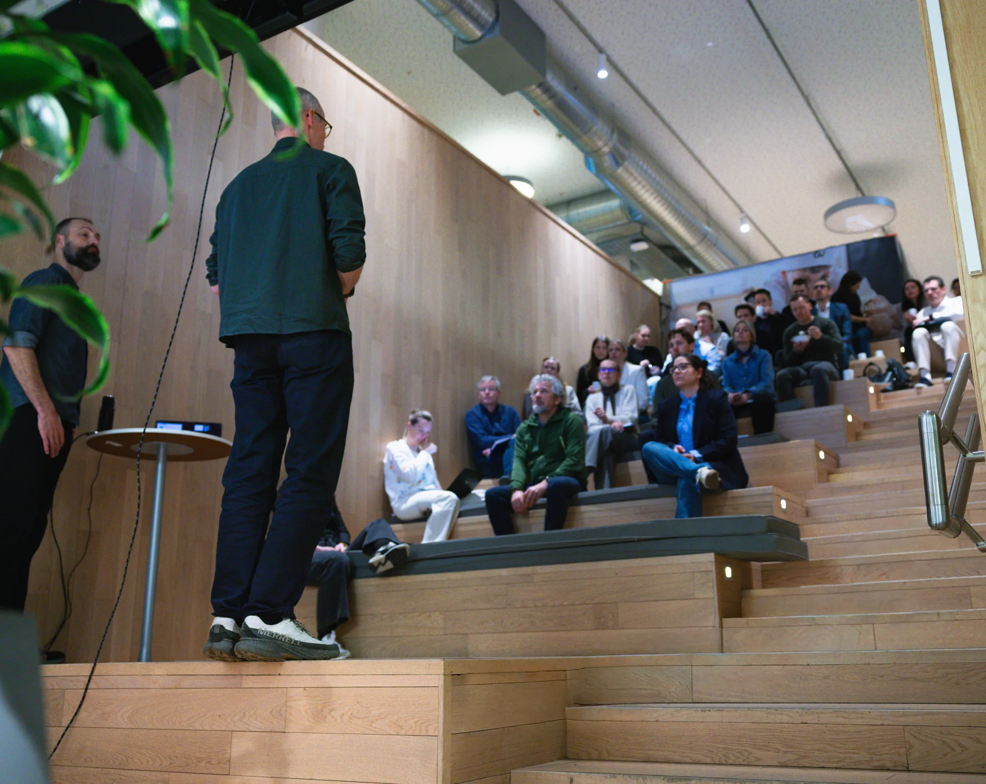 Trainer addresses a group of participants on the bleachers of an open training space